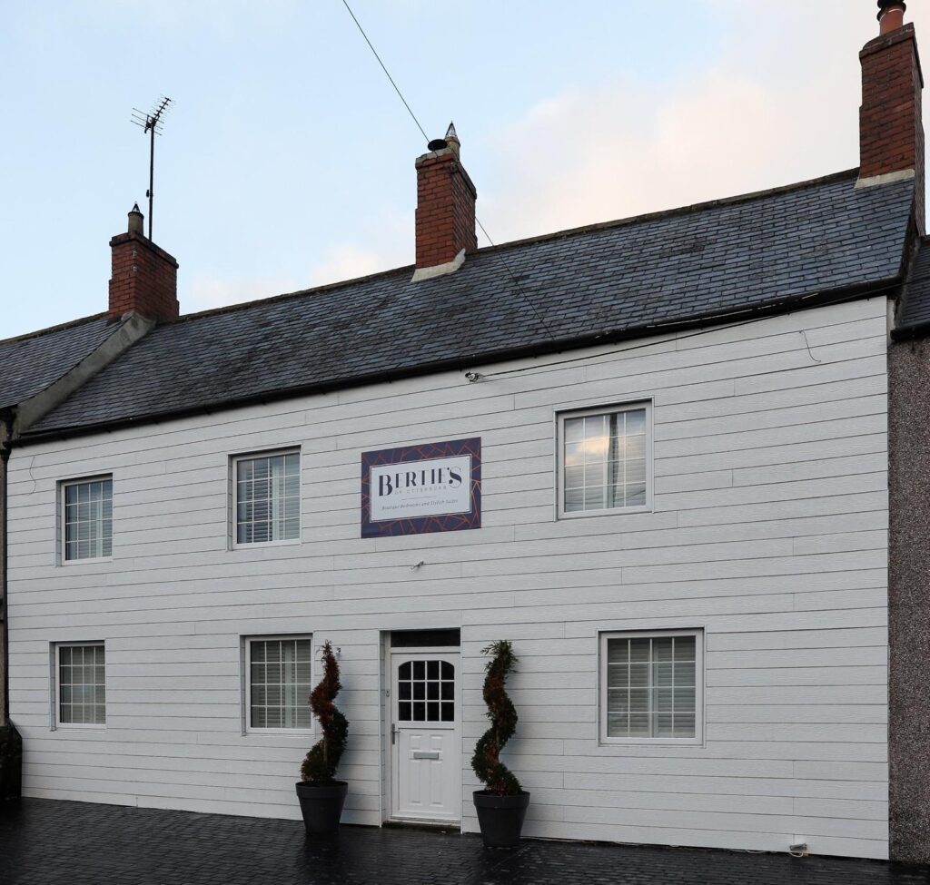 White-painted exterior of Berties of Otterburn with its sign above the entrance.