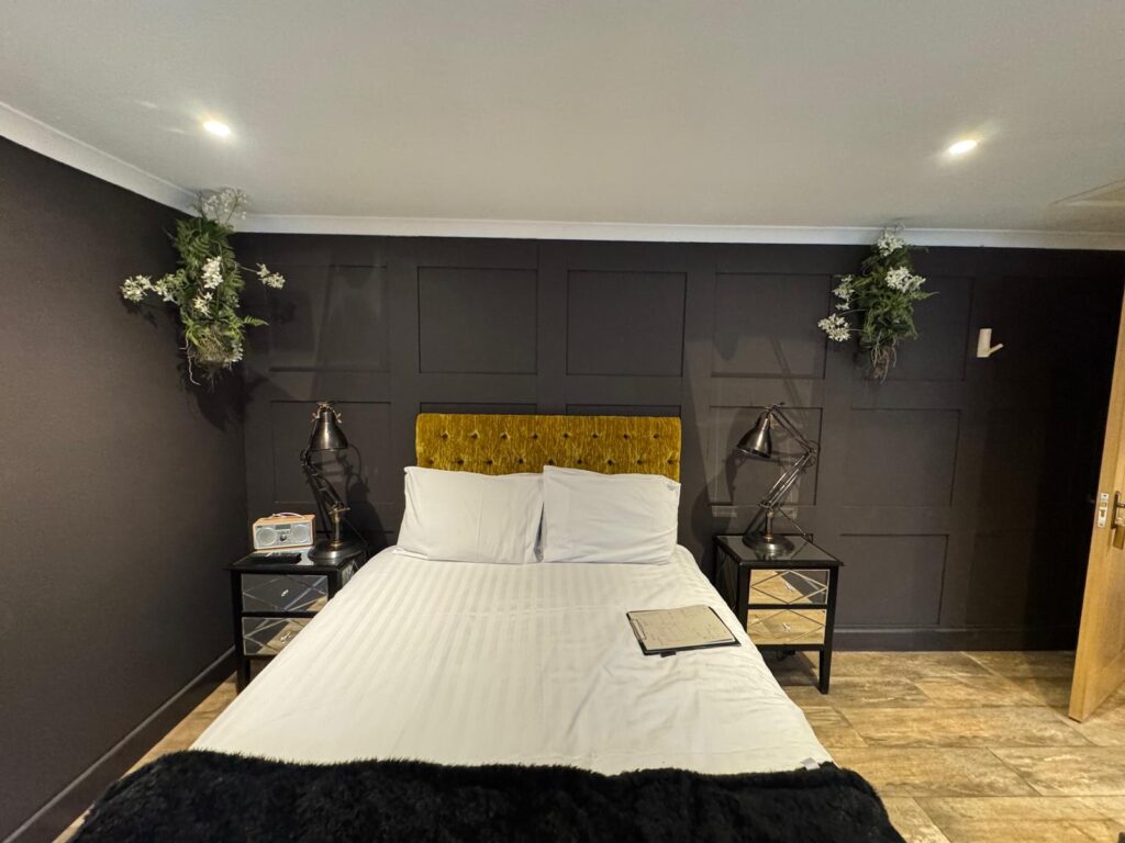 Compact mustard buttoned headboard against charcoal panelling, with mirrored bedside cabinets.