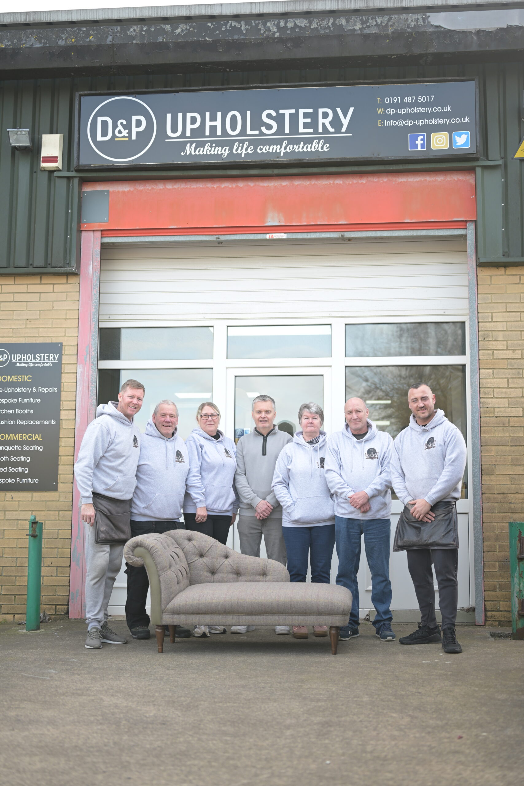 The D&P team with furniture and their workshop sign