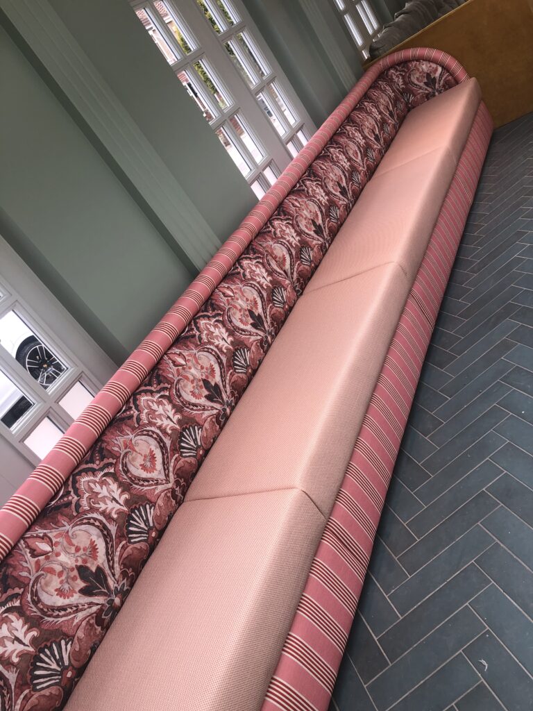Angled view of the finished pink banquette and its continuous patterned back.