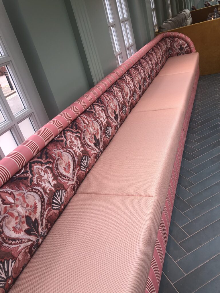 View along the pink banquette showing the seat divisions and striped top edge.