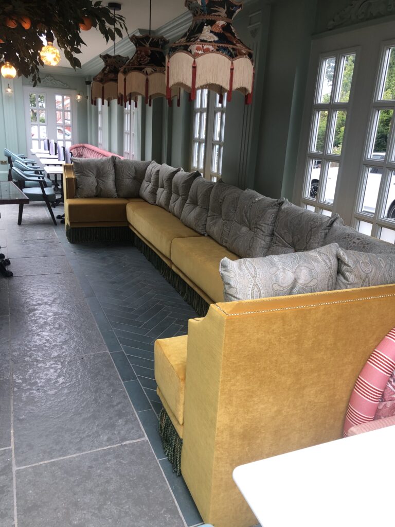 Mustard seating and patterned cushions in a bright room with decorative hanging lamps.