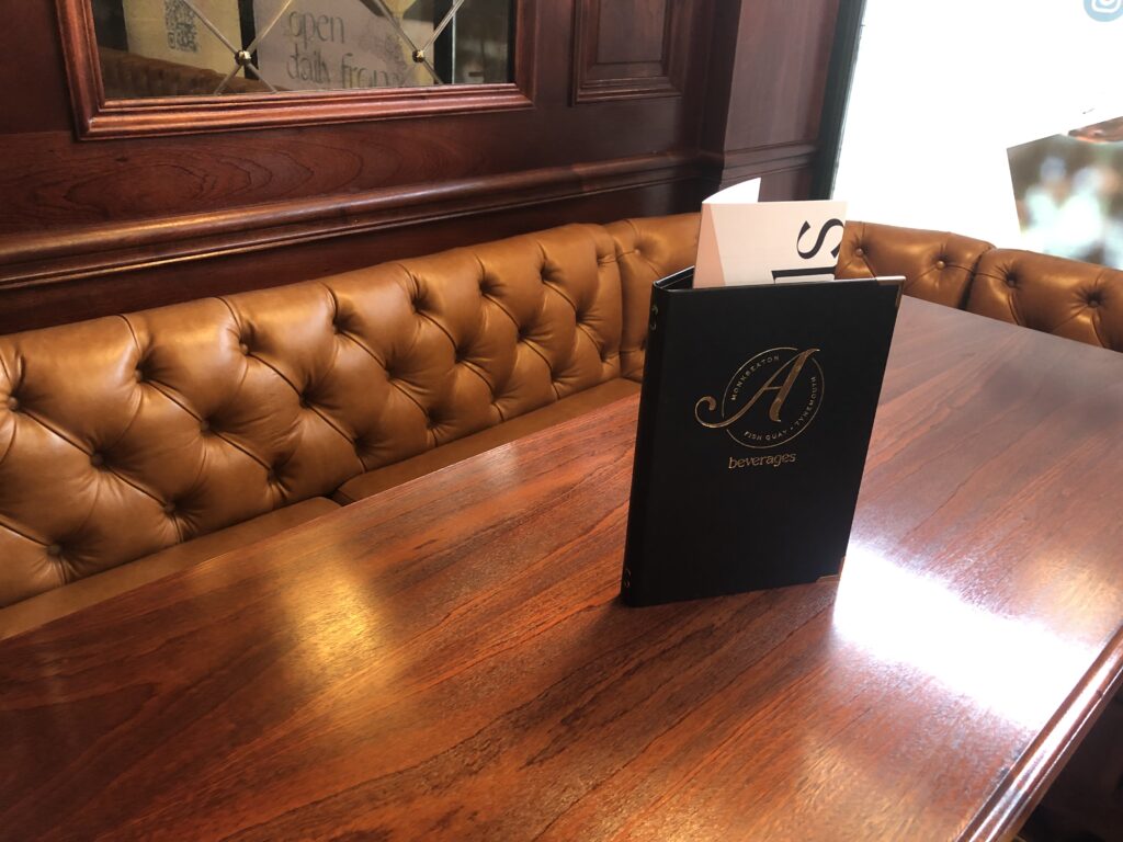 Close view of the tan buttoned banquette against dark timber panelling.