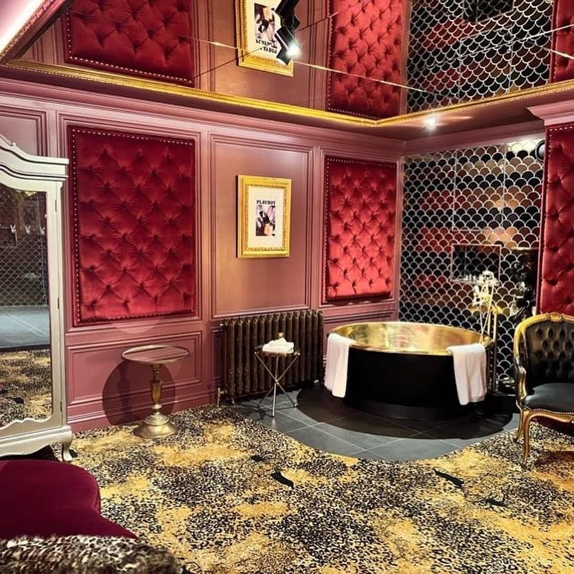 Burgundy upholstered wall panels with studded borders around a mirrored bathing area.