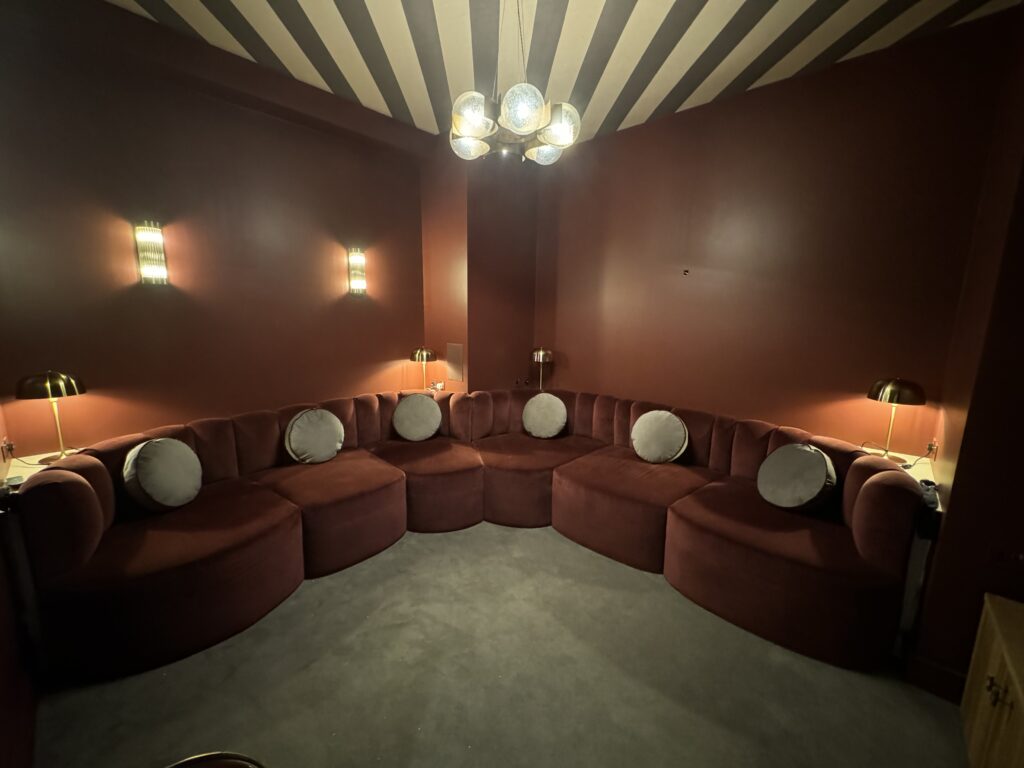 Front view of rust-coloured wraparound seating with round pale cushions and curved seat fronts.