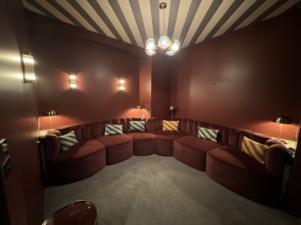 Wide front view of rust-coloured wraparound seating dressed with blue and ochre striped scatter cushions.