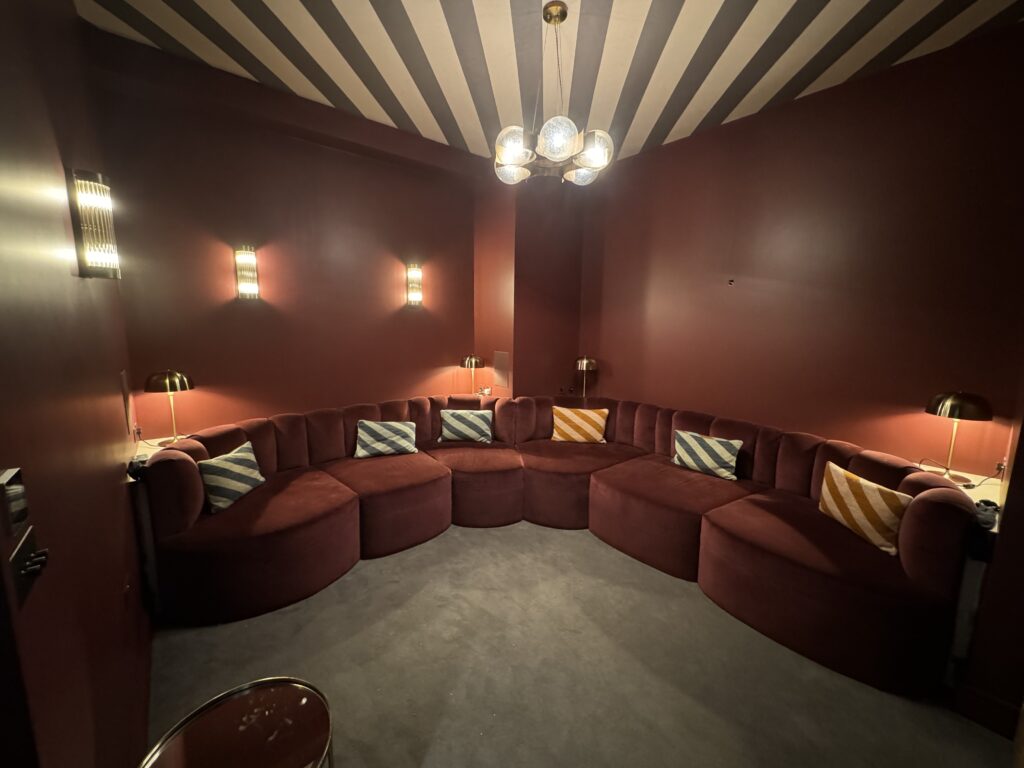 Rust-coloured wraparound seating with rounded seat fronts and striped scatter cushions under a striped ceiling.